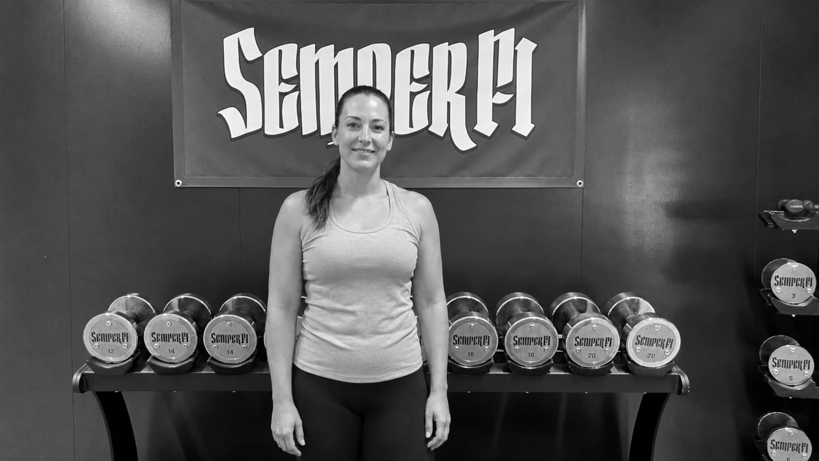kundin-1-semper-fi-body-concept-personal-trainer-baden Eine zufriedene semper fi Kundin steht vor der semper fi Signature Wall und macht einen glücklichen Eindruck.
