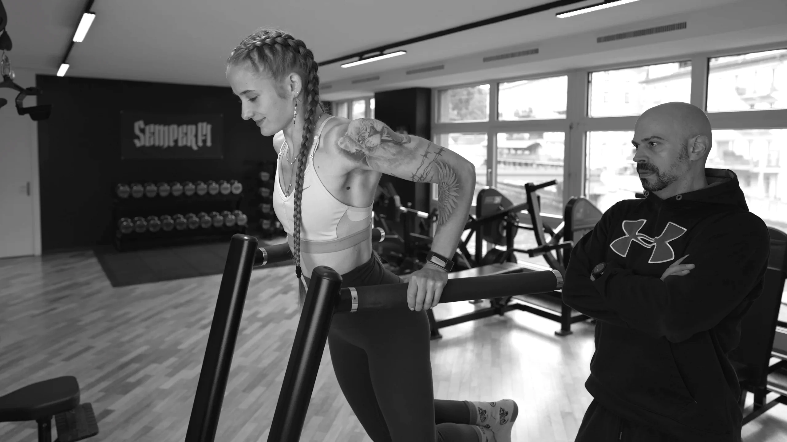 athletin-triceps-dip-bikini-athletin-coach-semper-fi-body-concept Eine Athletin macht Triceps Dips. Der Coach steht hinter ihr und beobachtet ihre Ausführung.