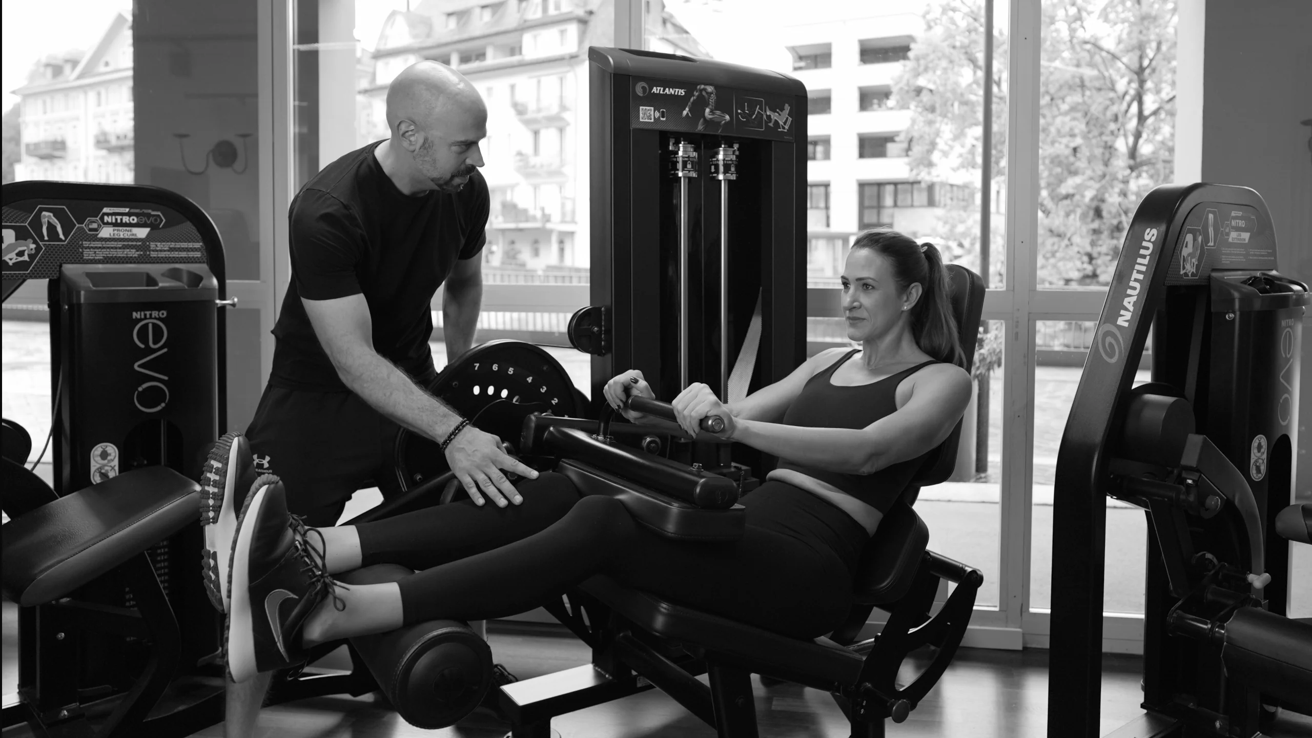 frau-beinbeuger-sitzend-mit-coach-semper-fi-body-concept-personal-trainer-baden Eine Frau führt sitzendes Beinbeugen aus. Der Coach gibt ihr Anweisungen zur Übungsausführung.