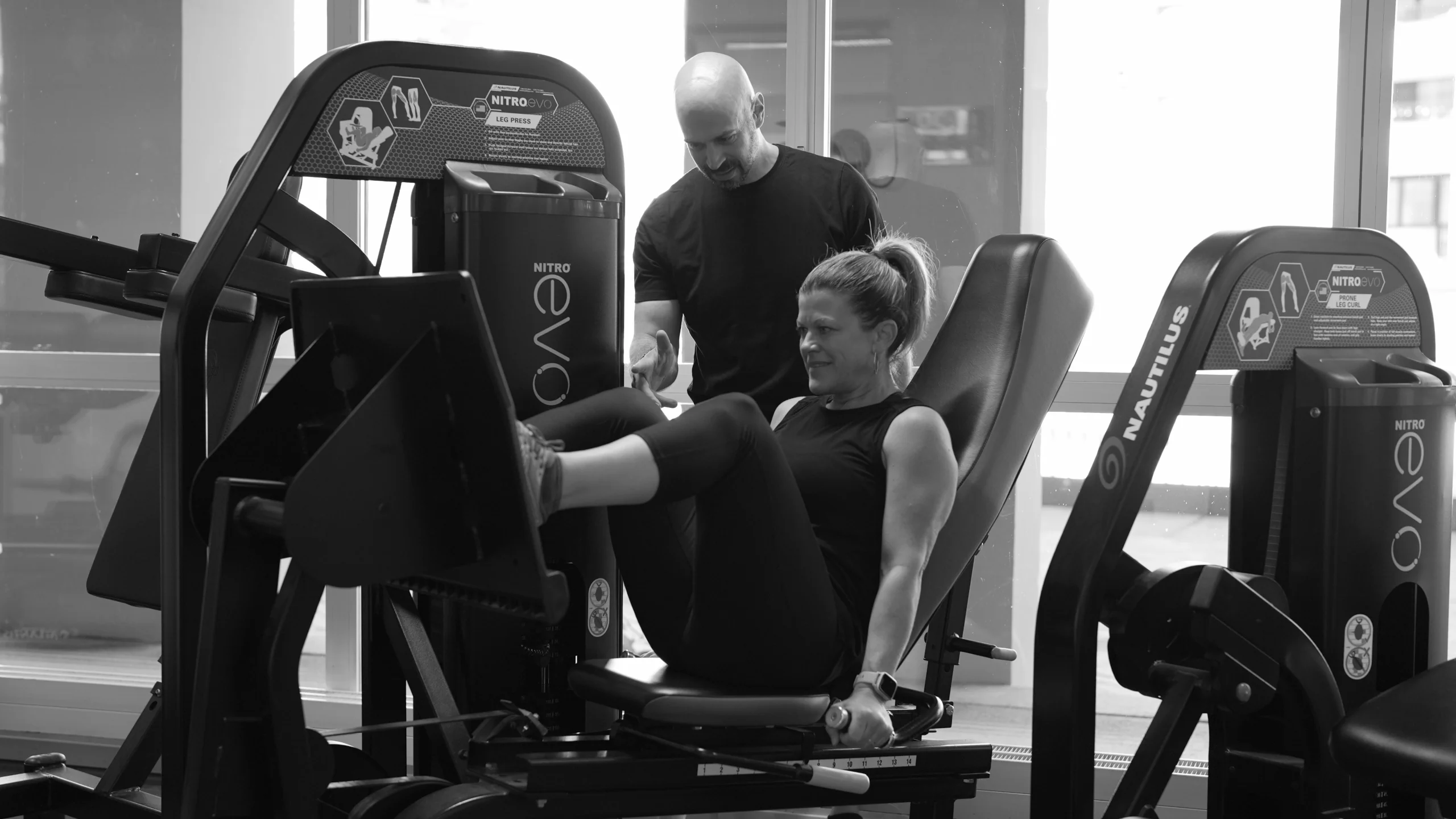 frau-beinpresse-mit-coach-semper-fi-body-concept-personal-trainer-baden Eine Frau sitzt auf der Beinpresse. Der Coach gibt ihr Anweisungen.