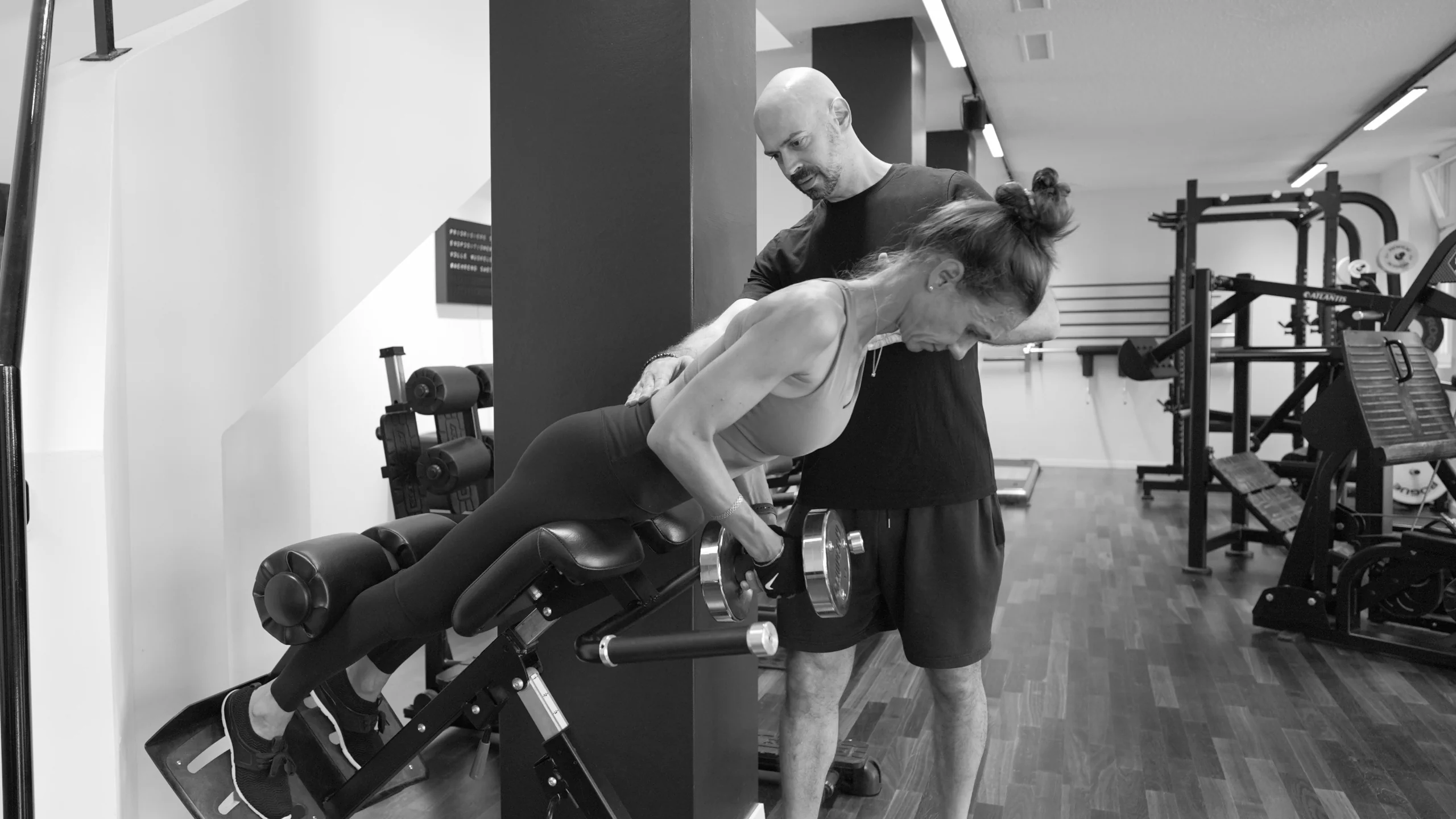 frau-hueftstreckung-45°-mit-coach-semper-fi-body-concept-personal-trainer-baden Eine Frau führt 45° Hüftstrecken mit der Kurzhantel aus. Der Coach korrigiert ihre Haltung währen der Übungsausführung.