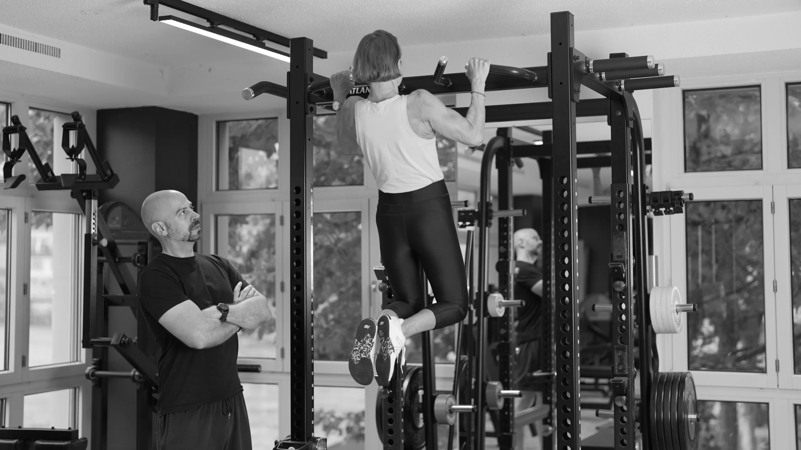 frau-klimmzug-mit-coach-semper-fi-body-concept-personal-trainer-baden Eine Frau macht Klimmzüge. Der Coach beobachtet ihre Übungsausführung.