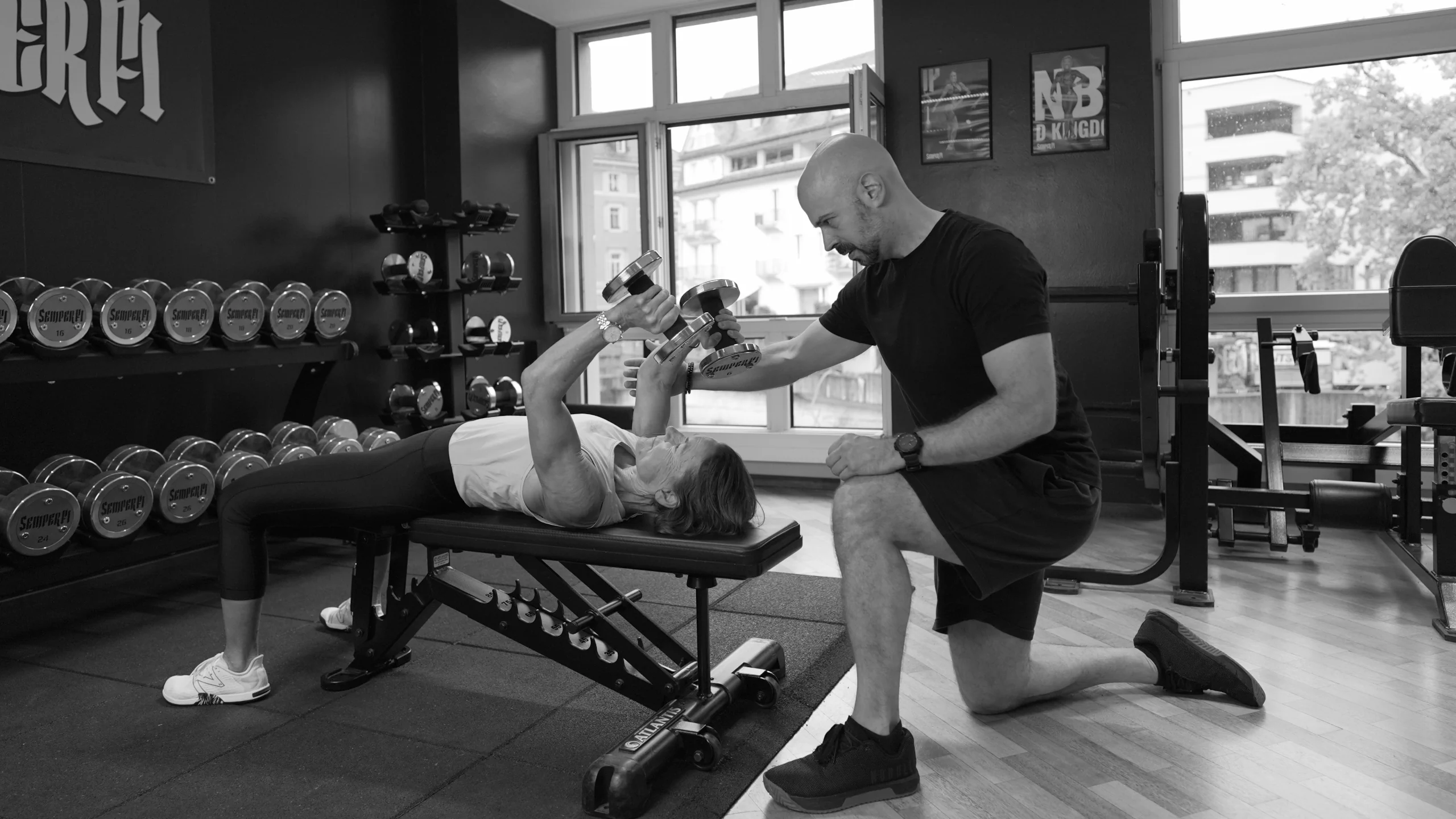 frau-triceps-strecken-mit-coach-semper-fi-body-concept-personal-trainer-baden Eine Frau liegt auf der Trainingsbank und führt Triceps Strecken mit Kurzhanteln aus. Der Coach kontrolliert die Übgunsausführung.