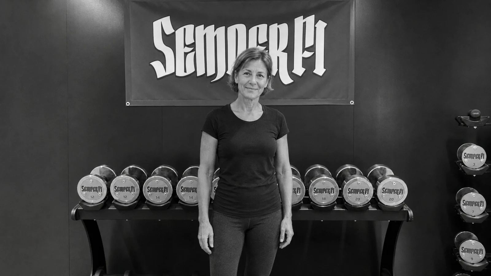 kundin-2-semper-fi-body-concept-personal-trainer-baden Eine weitere zufriedene semper fi Kundin steht vor der semper fi Signature Wall und lacht in die Kamera.